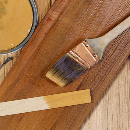 Interior StainsA brush and stir stick on top of freshly stained wood.